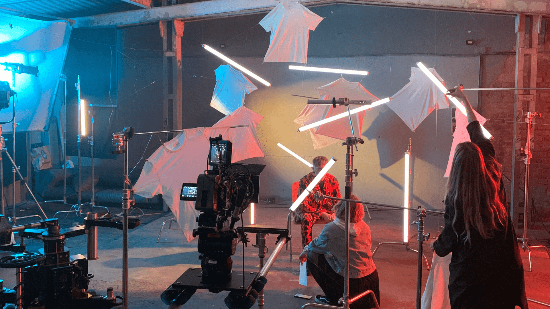 Zdjęcie ze studio fotograficznego. W tle kamera, oświetlenie oraz zespół.