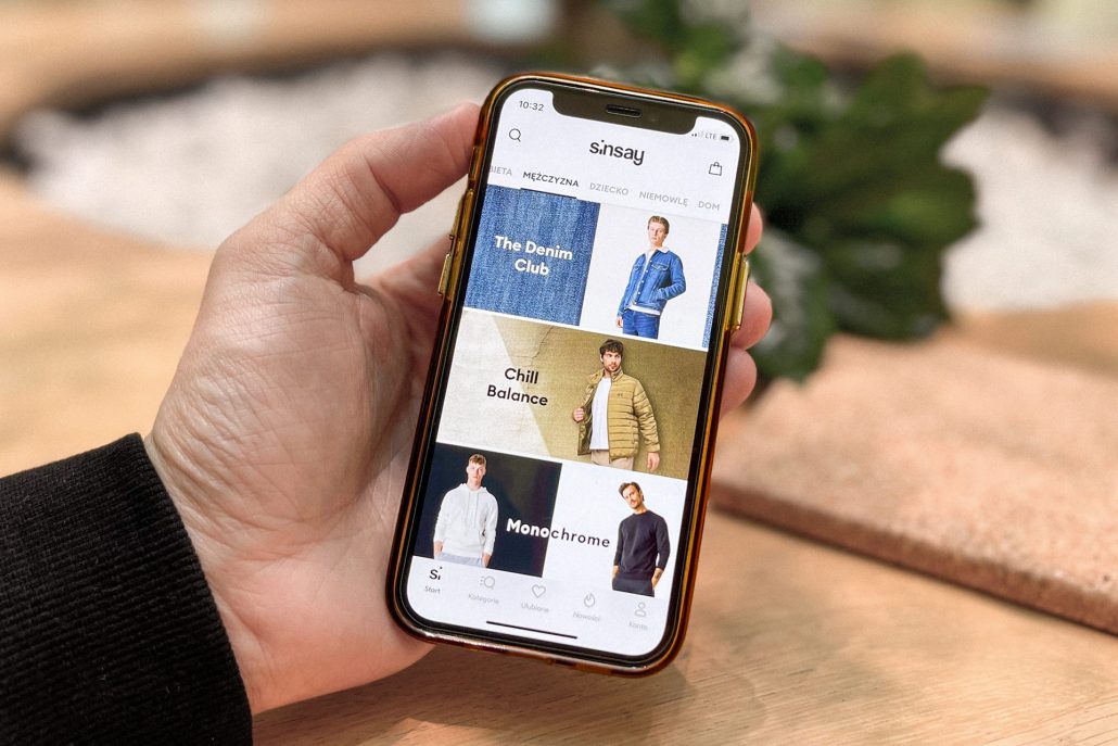 W męskiej dłonie telefon marki iPhone z otwartą aplikacją Sinsay