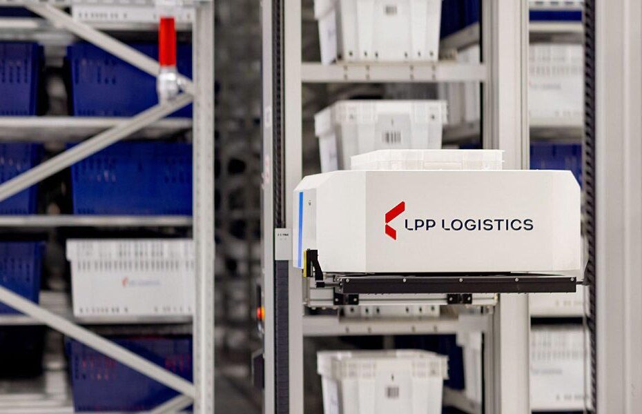 Automated warehouse robot labeled 'LPP LOGISTICS' moving along a rack with blue bins in the background.