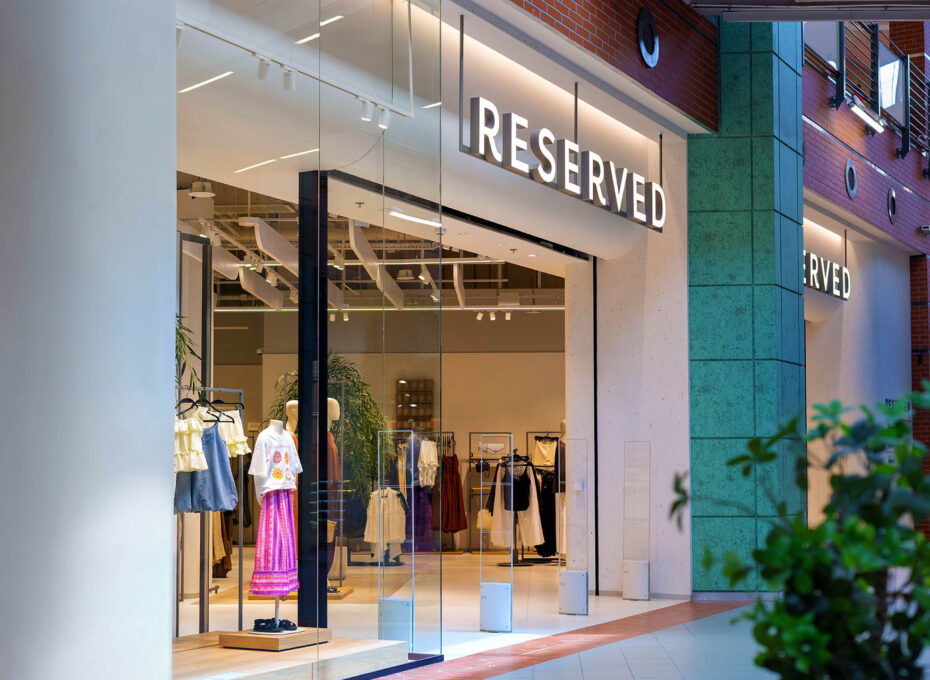 Shopfront of a RESERVED clothing store with mannequins in the window and glass doors inside a mall.